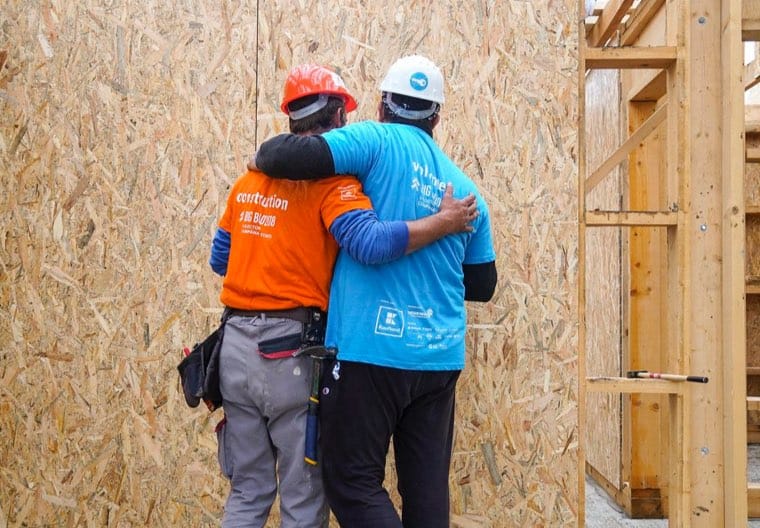 Volunteers helping one another build a home